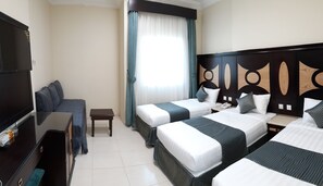 A hotel room with two beds, a TV, a desk, and a window with curtains. - Diyar Al-Mashaer Hotel  (Makkah)