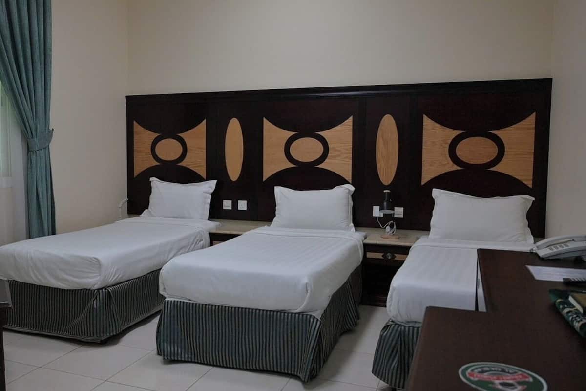 Una habitación de hotel con dos camas individuales, un escritorio con teléfono y una silla.