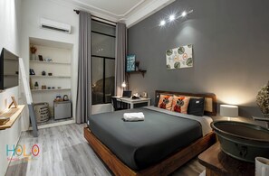 Een moderne hotelkamer met een groot bed, een bureau met een laptop, een televisie en een raam met gordijnen.