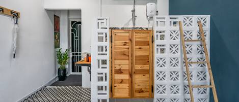 Un baño con piso estampado, una puerta de madera, una separación blanca y una escalera.