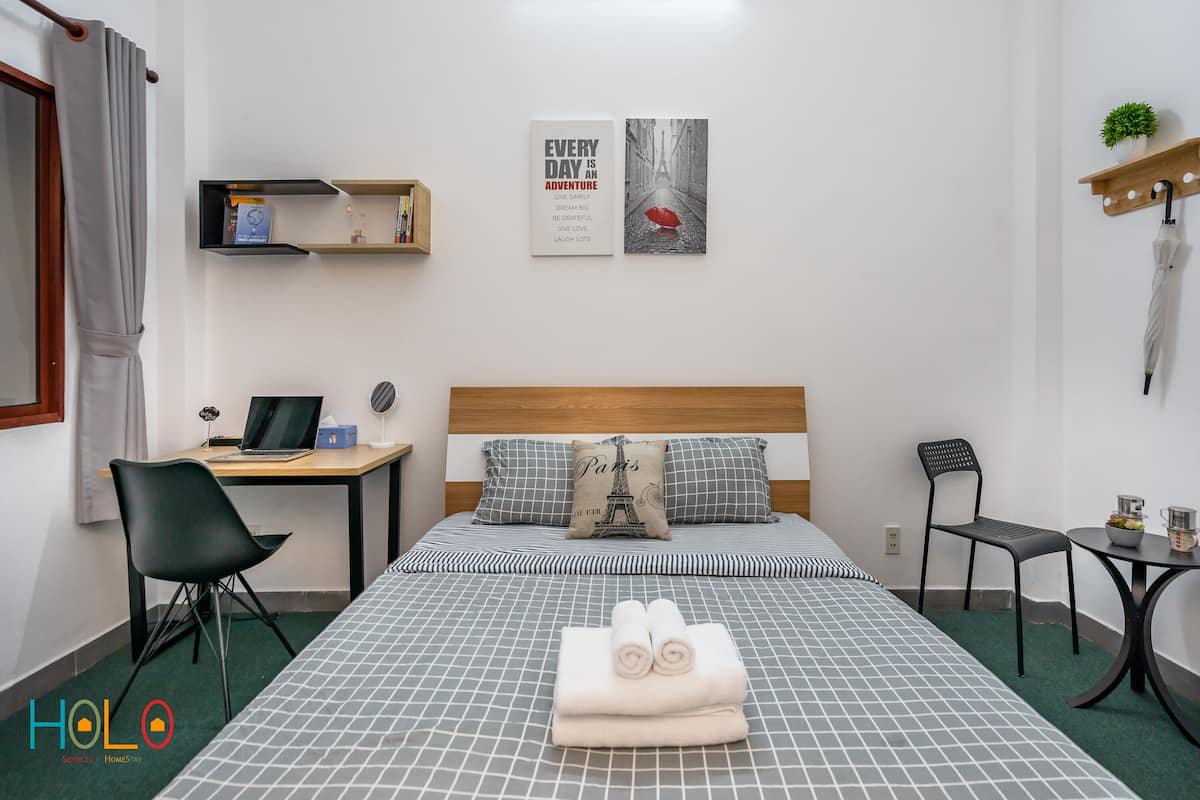 A neatly arranged hotel room with a bed, two chairs, a desk, and a small table.