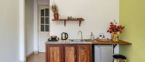 Una cocina compacta con armarios de madera, un lavamanos empotrado y un refrigerador pequeño.