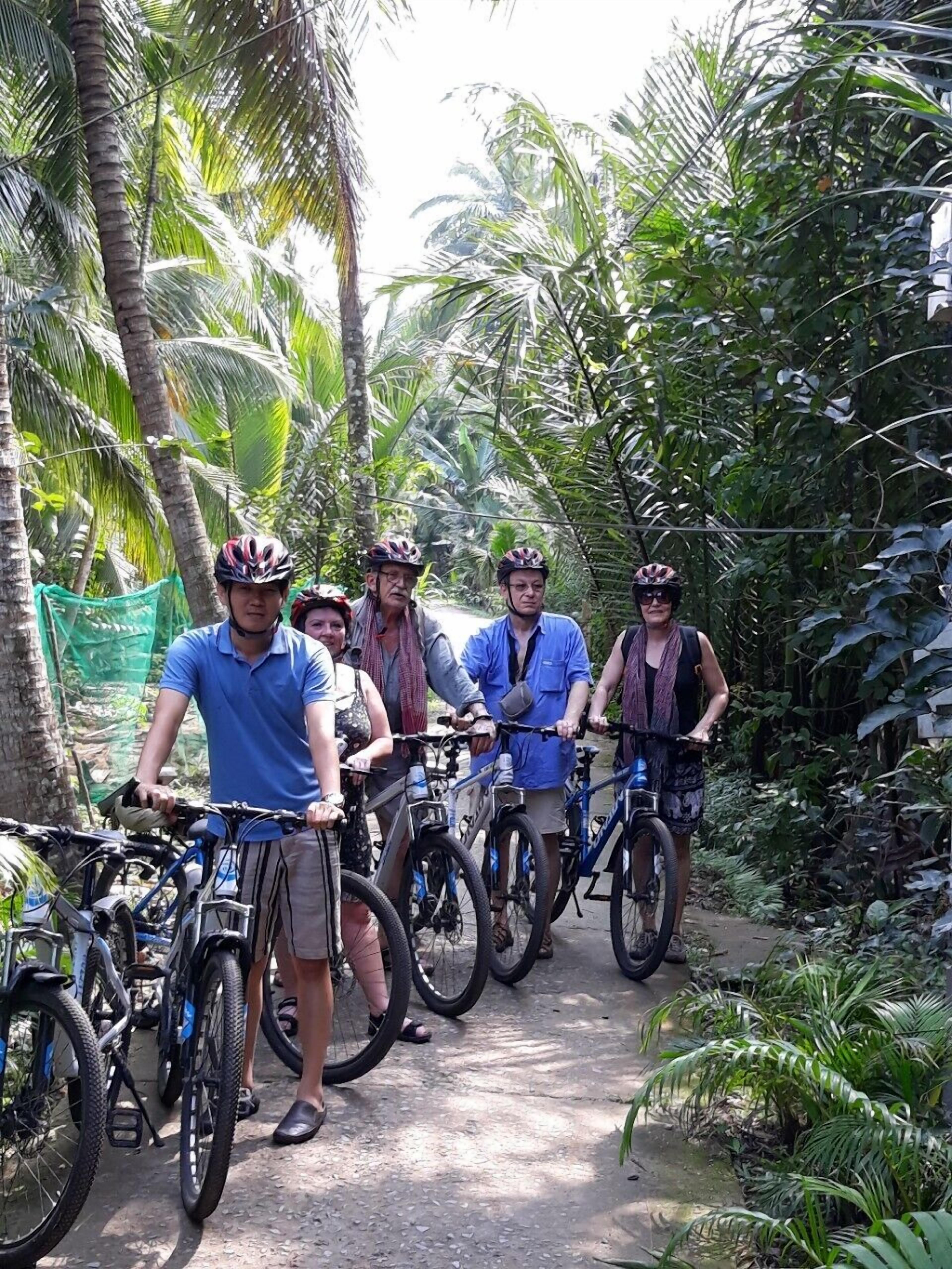 Um grupo de pessoas em bicicletas em um cenário tropical com vegetação densa.