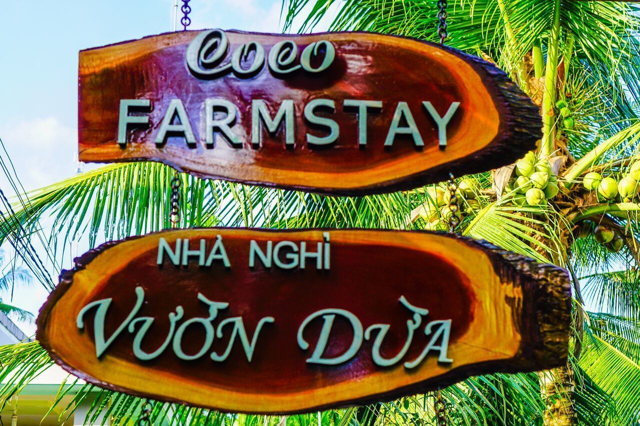 Une pancarte en bois sur laquelle sont inscrits les mots « Coo Farmstay » et « Nha Nghi Vung Dua ».