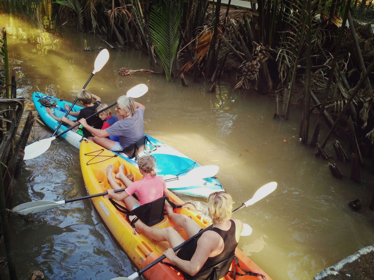 Eine Gruppe von Menschen paddelt in einem ruhigen Fluss, der von dichter Vegetation gesäumt wird.
