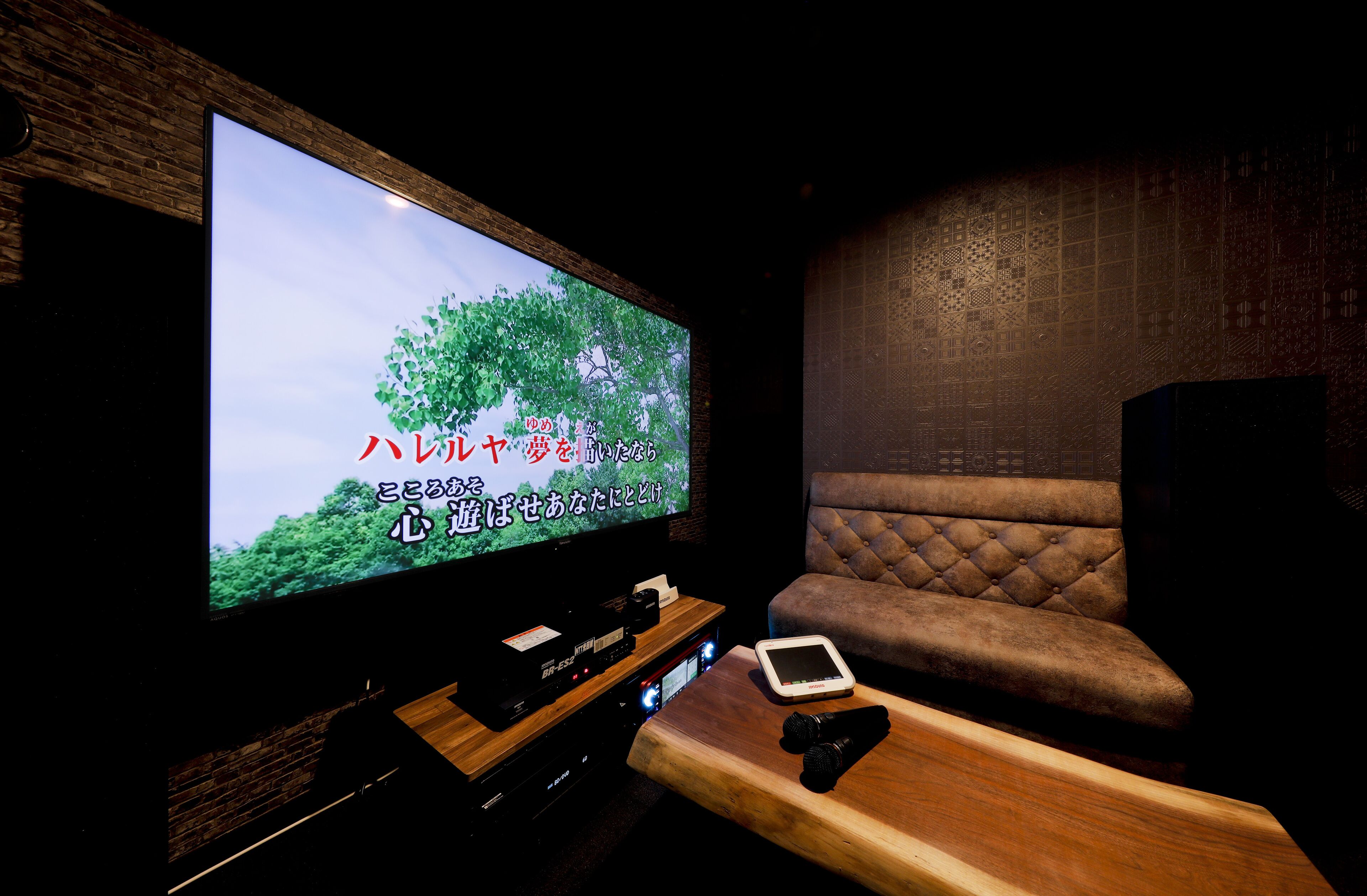 A modern living room with a large flat-screen TV, a wooden coffee table, and a cushioned seating area.