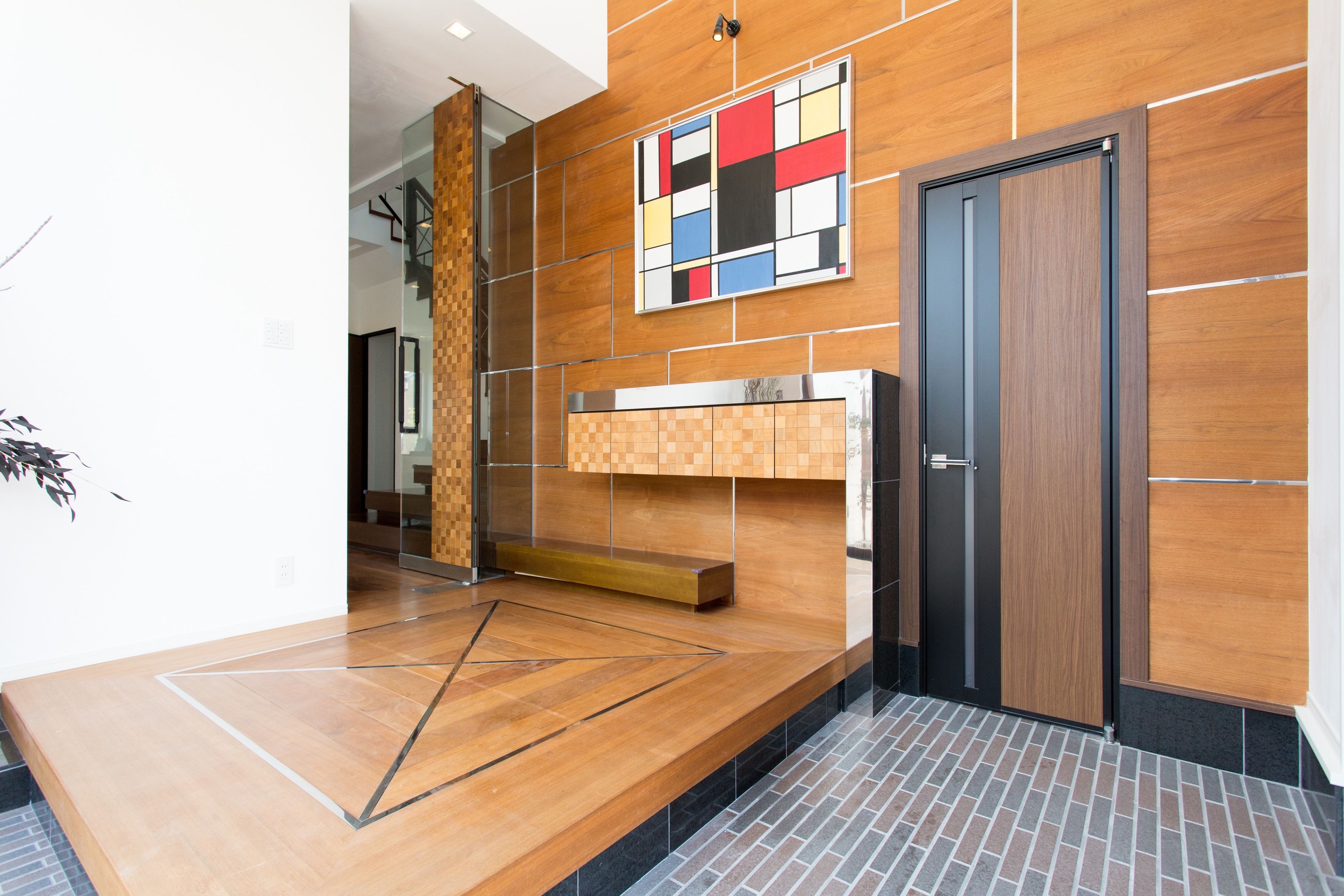 A modern lobby with a wooden wall, a geometric floor design, a colorful abstract artwork, and a dark door.