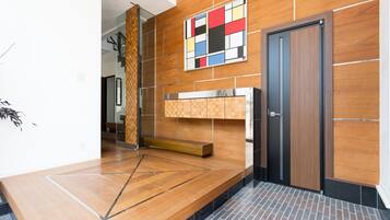 A modern lobby with a wooden wall, a geometric floor design, a colorful abstract artwork, and a dark door.