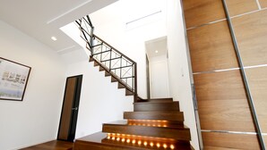 Eine moderne Treppe mit Holzstufen und einem Metallgeländer, die zu einer Zwischenebene mit einer Tür führt.