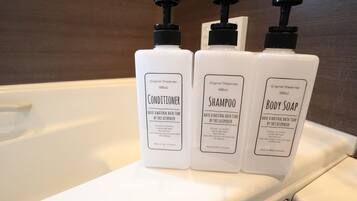 Three bottles of conditioner, shampoo, and body soap on a white surface.