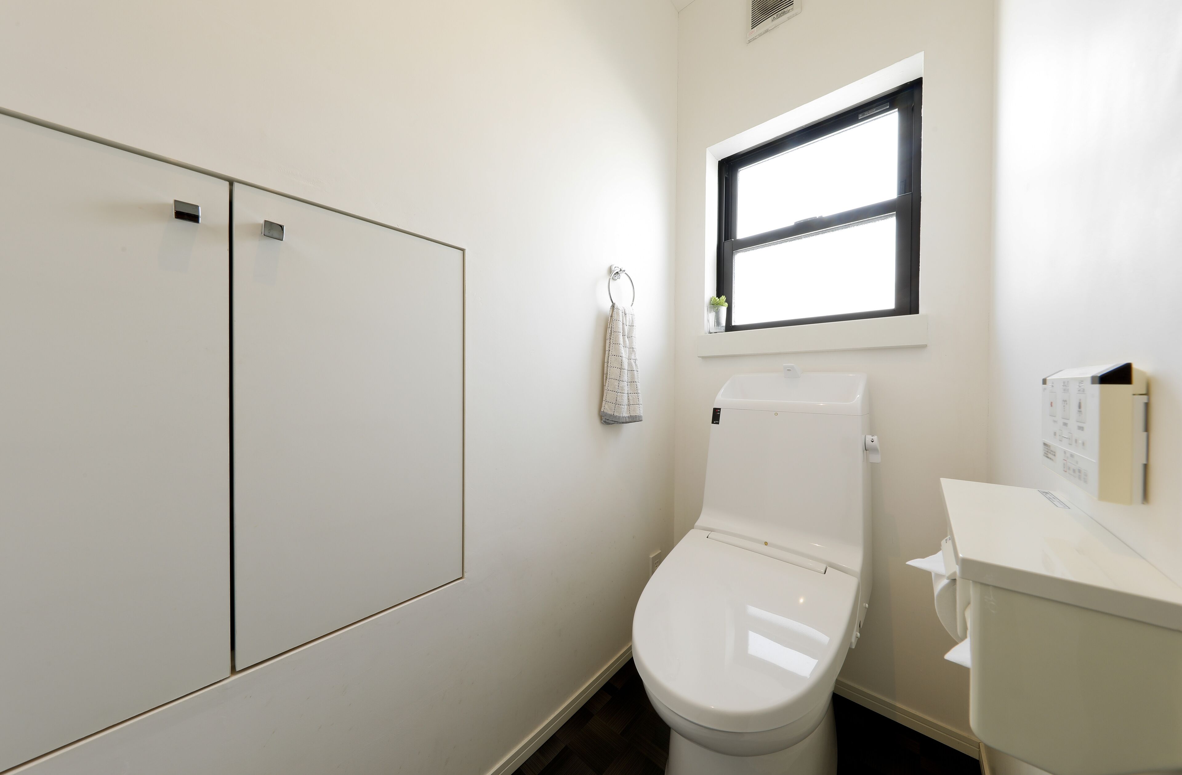 Un bagno piccolo e pulito con il water, una finestra e un asciugamano appeso a un gancio.