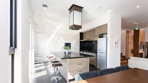 Eine moderne Küche mit Kochinsel, Barhocker und einem Essbereich mit Holztisch.