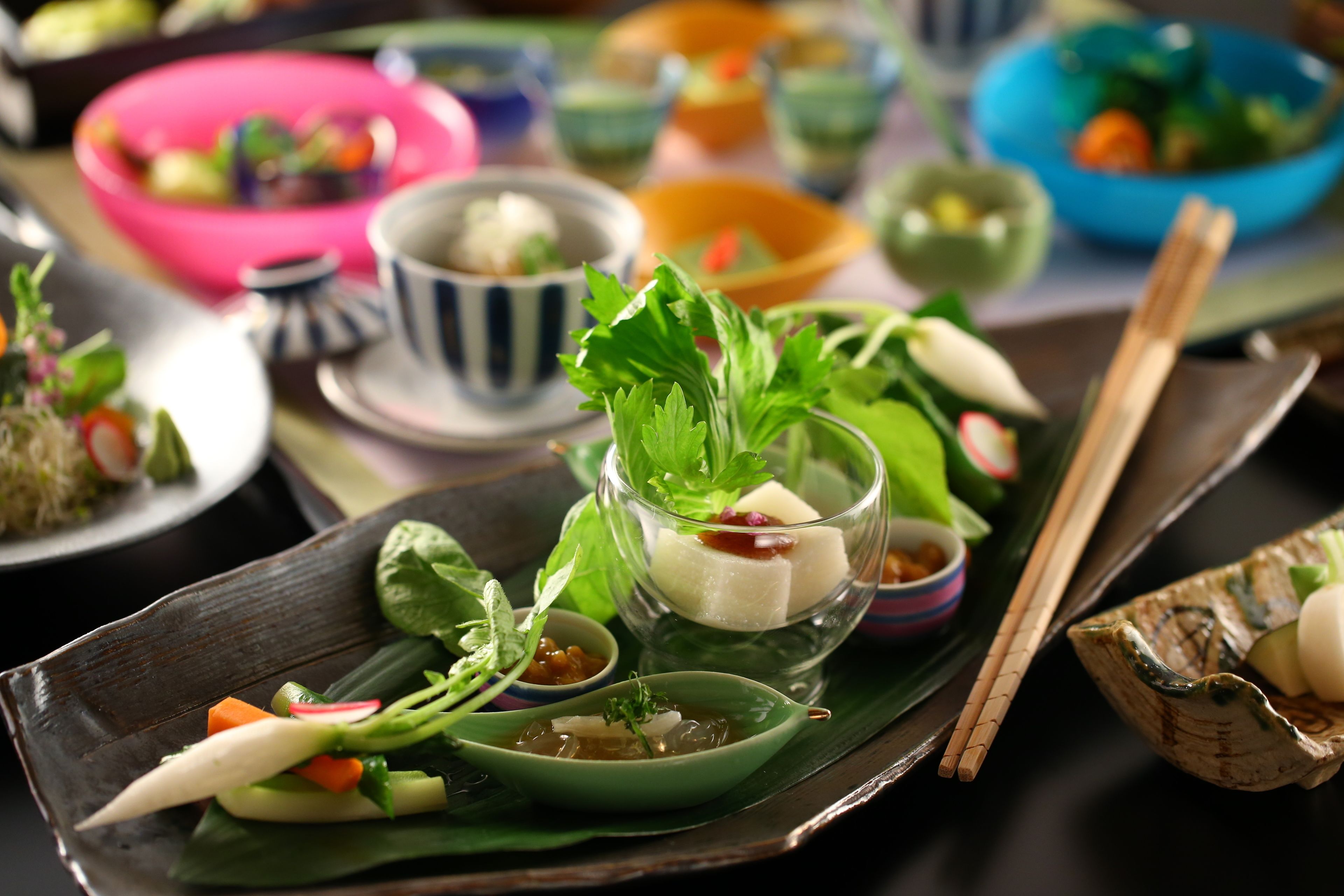 Variedad de platos en una mesa, incluyendo un tazón de sopa, un plato con verduras y un vaso con postre.