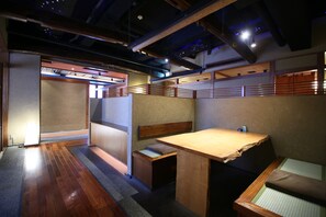 Ein traditioneller japanischer Raum mit Tatami-Bodenbelag, einem niedrigen Holztisch und einer gepolsterten Bank.