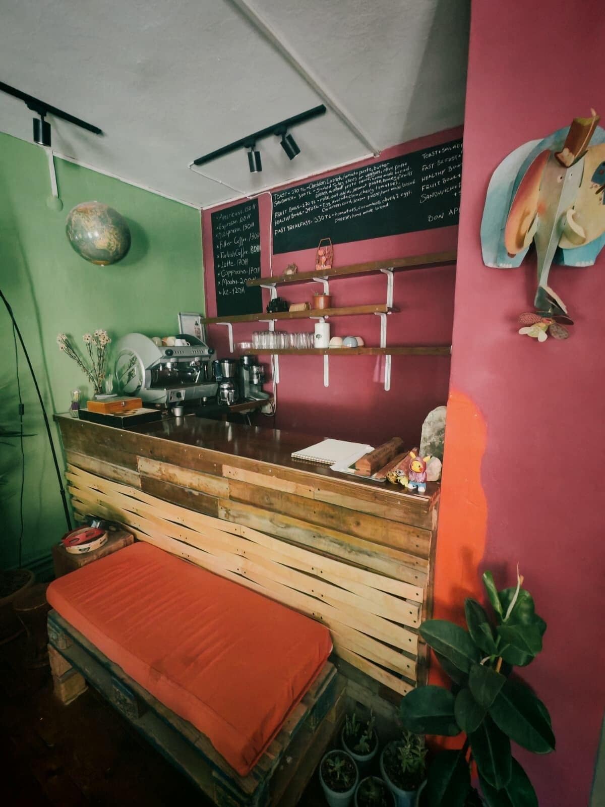 A compact kitchen with a wooden counter, a chalkboard menu, and a small seating area with a bench.