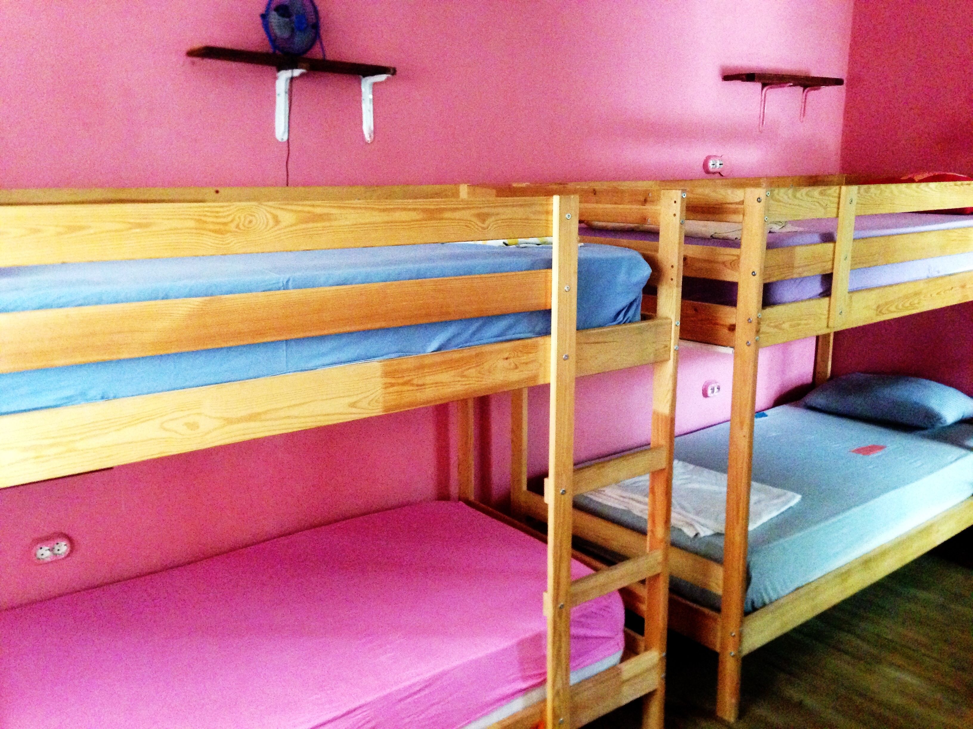 A bunk bed room with pink walls and wooden bunk beds.