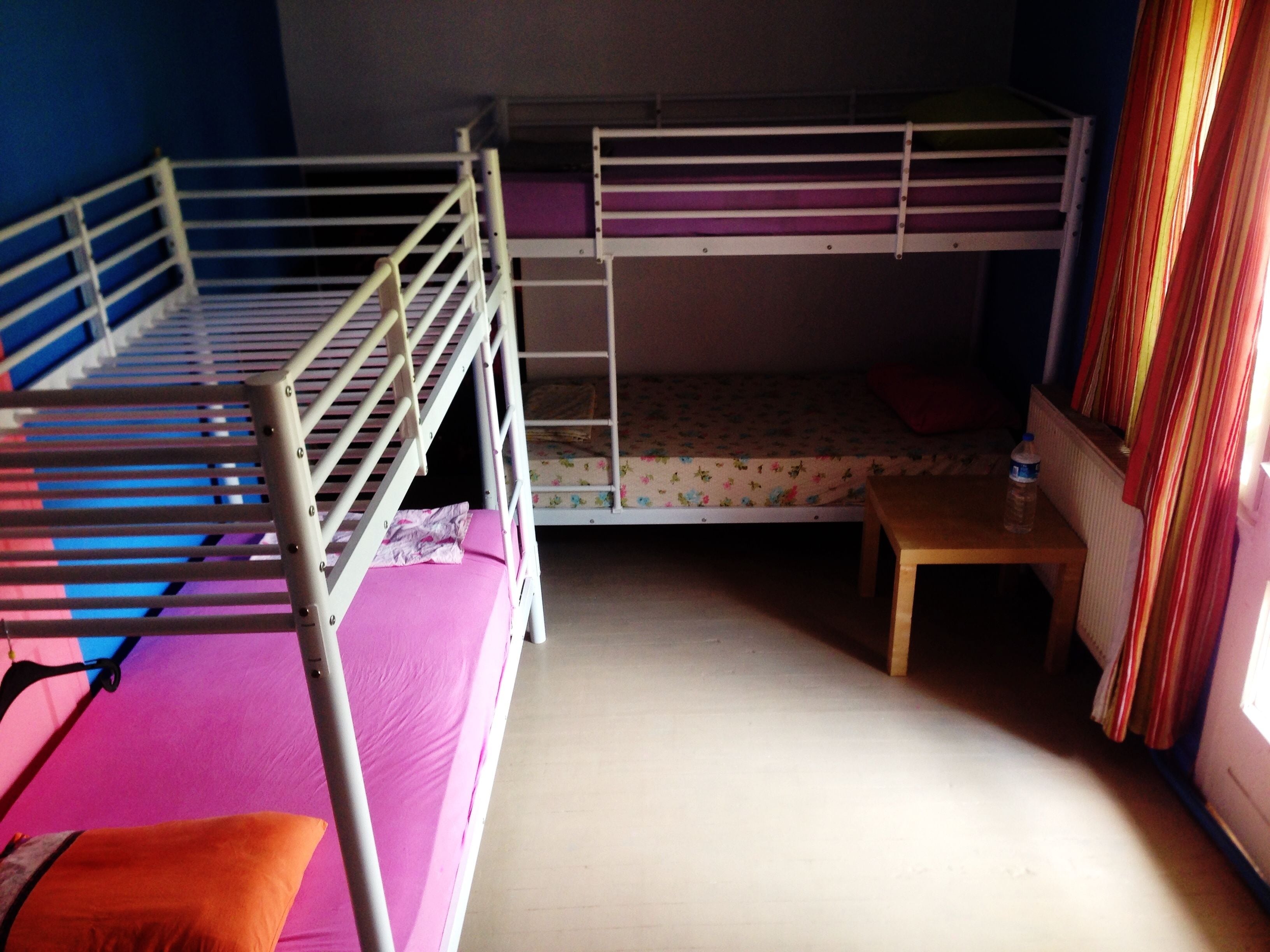 A bunk bed room with a wooden table and a water bottle.