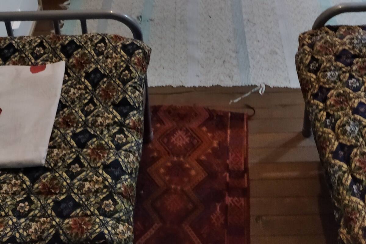 A room with a bed, a radiator, a window with curtains, a fan, and patterned furniture.