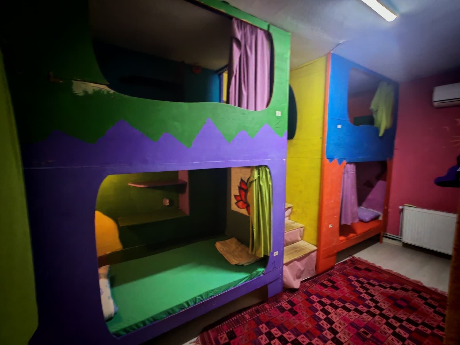 A bunk bed room with a green and purple color scheme, a patterned rug, and a radiator.