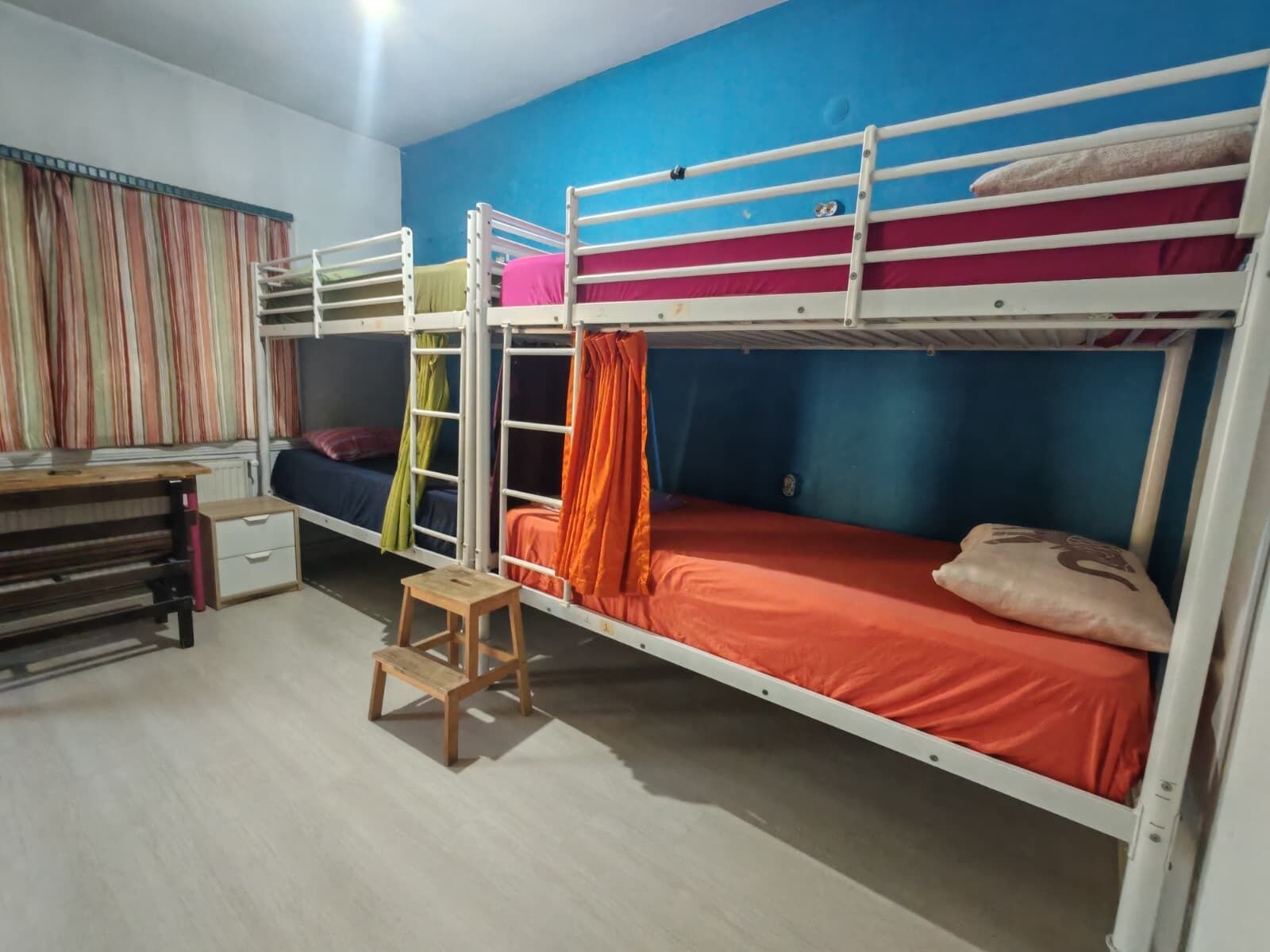 A dormitory room with bunk beds, a desk, and a chair.