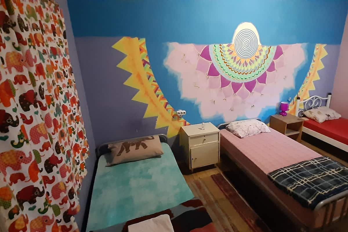 A bedroom with two beds, a dresser, and a wall mural.