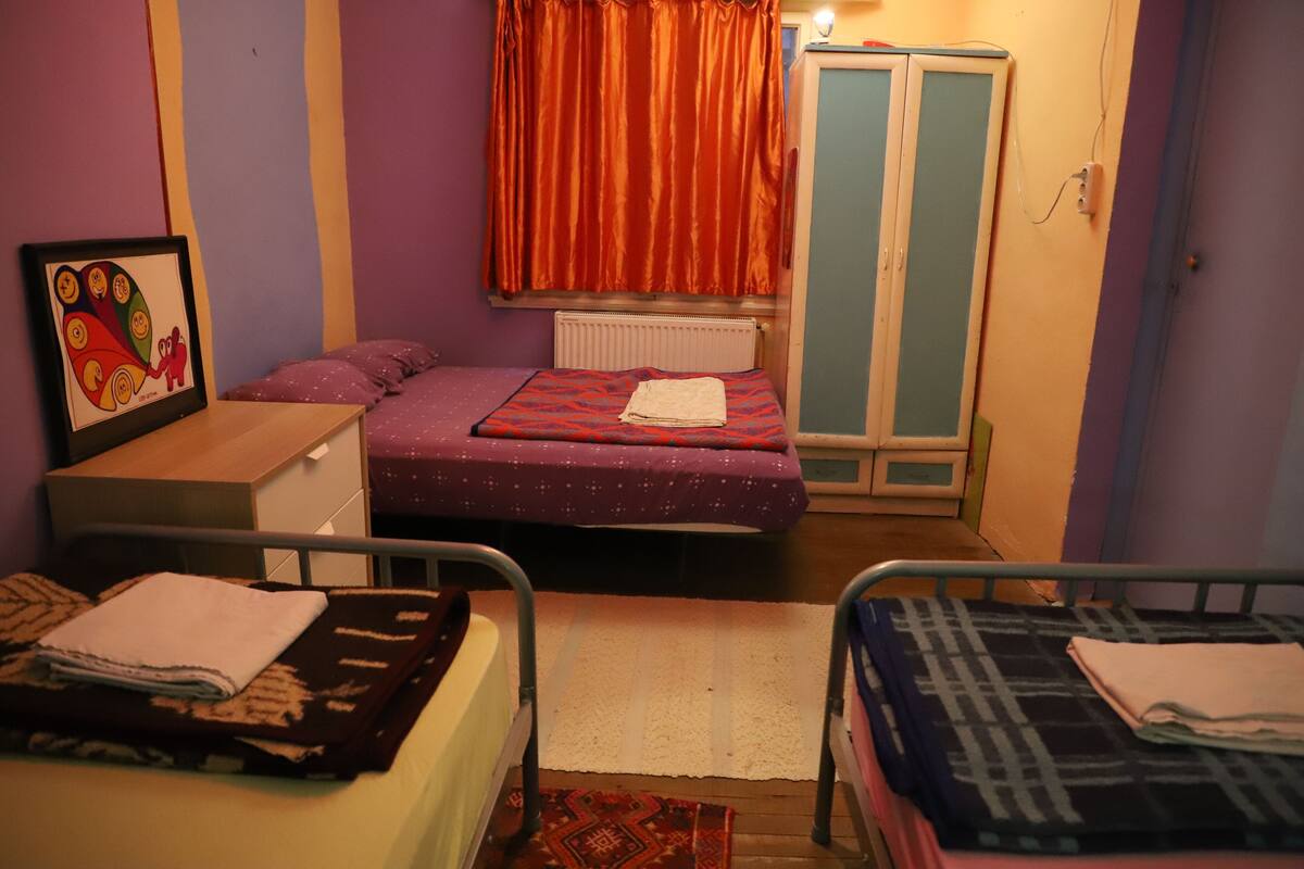 A bedroom with a bed, a nightstand, a dresser, a wardrobe, and a radiator.