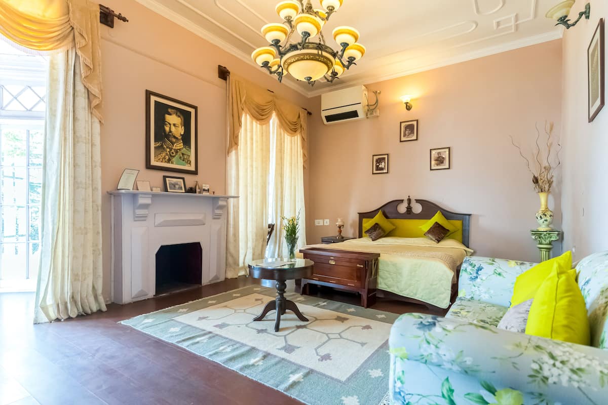 Une chambre à coucher comprenant un lit, une table de chevet, une commode, une cheminée et un lustre.