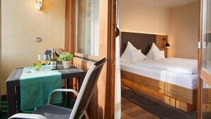 A room with a bed, a table with a green tablecloth, and a chair. - Landgasthof Zum Lamm (Bahlingen)