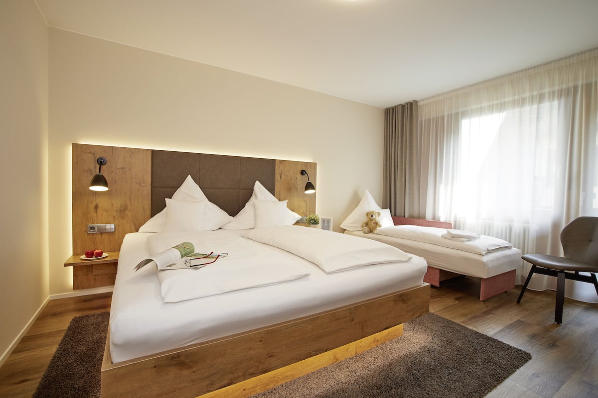 Una cama grande con cabecera de madera, mesitas de noche y una silla.
