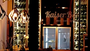 A well-lit interior with a display of wine bottles and a sign reading "Kaiser Bar". - Landgasthof Zum Lamm (Bahlingen)