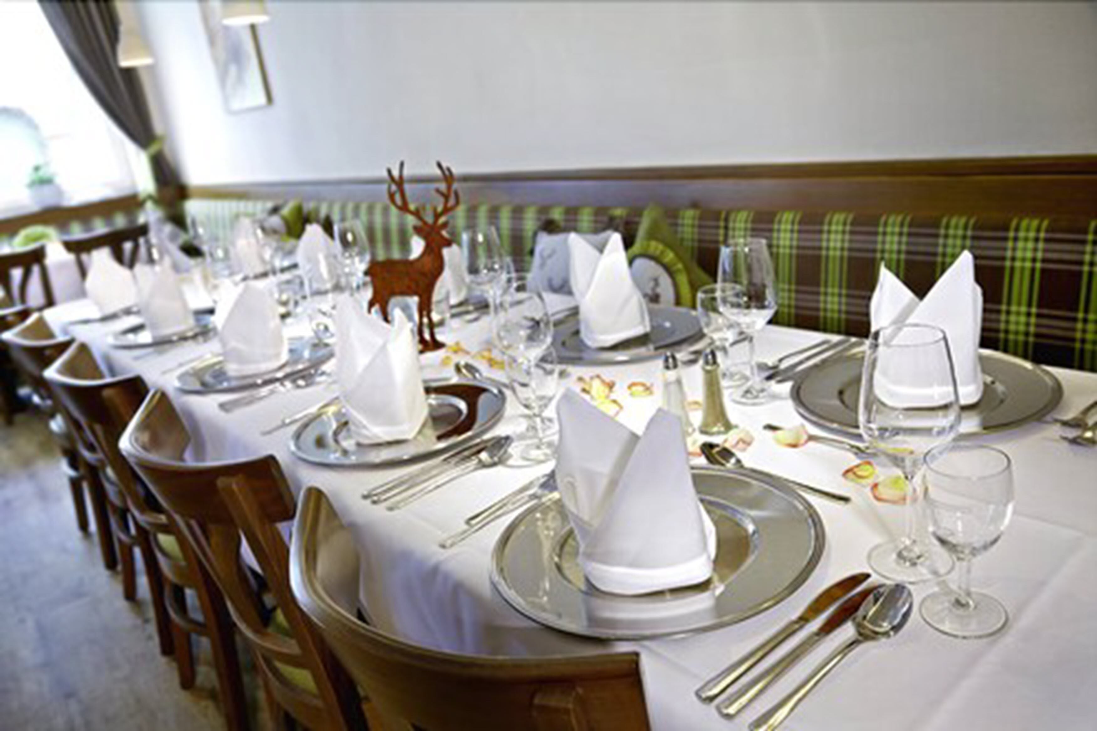 A restaurant with neatly set tables, each with white tablecloths, silverware, and glassware.