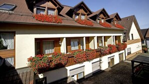 A two-story building with a sloped roof, dormer windows, and flower boxes on the balconies. - Landgasthof Zum Lamm (Bahlingen)