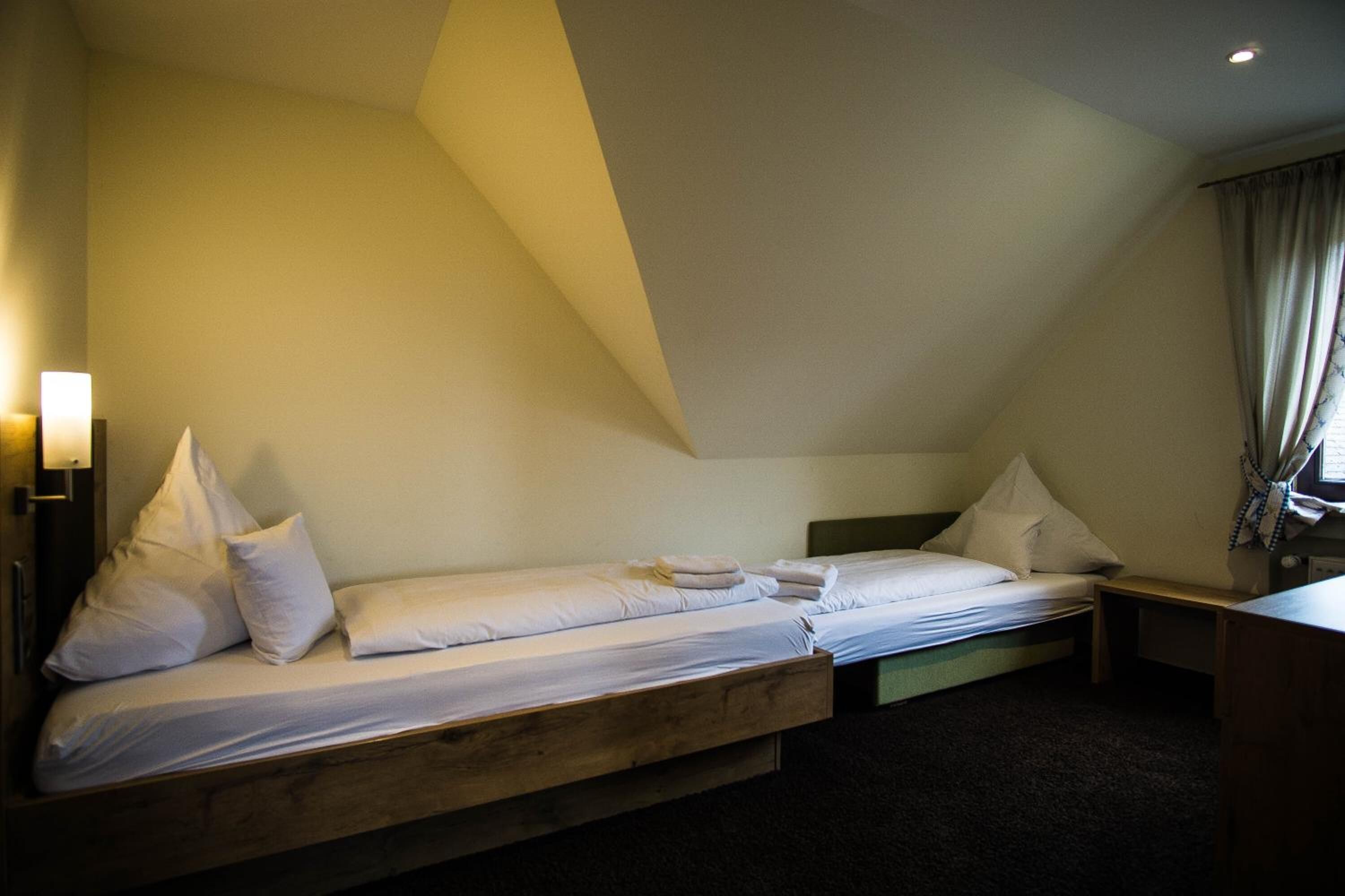 A single bed with a wooden headboard, a bedside table, and a lamp.