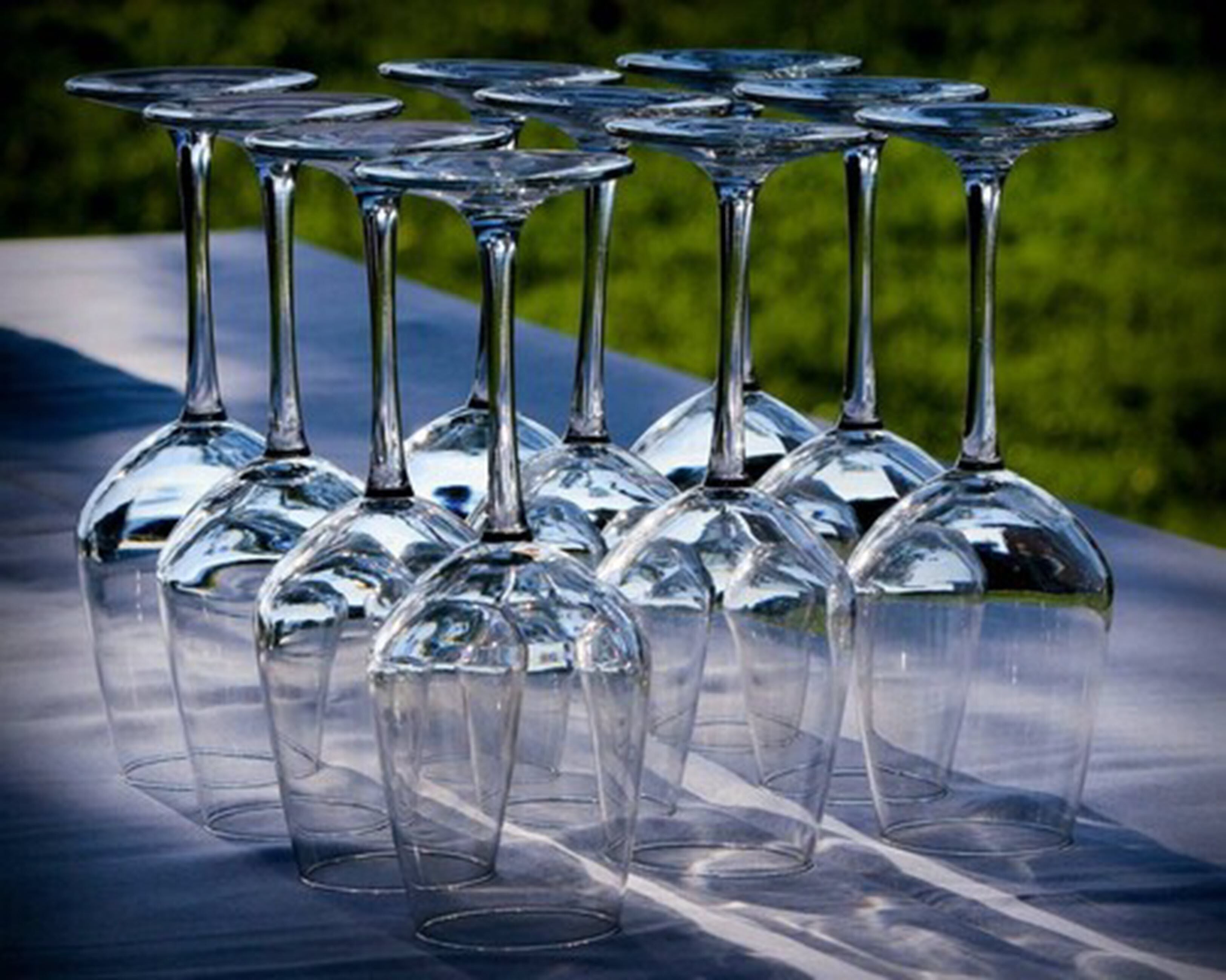 Une rangée de verres à vin vides sur une surface réfléchissante.