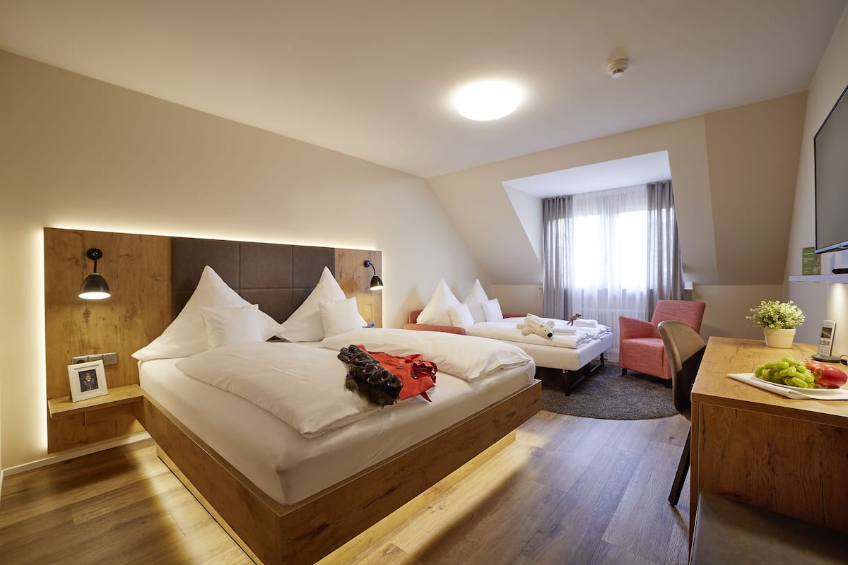 Una habitación de hotel moderna con una cama grande, un escritorio y una pequeña zona de estar.