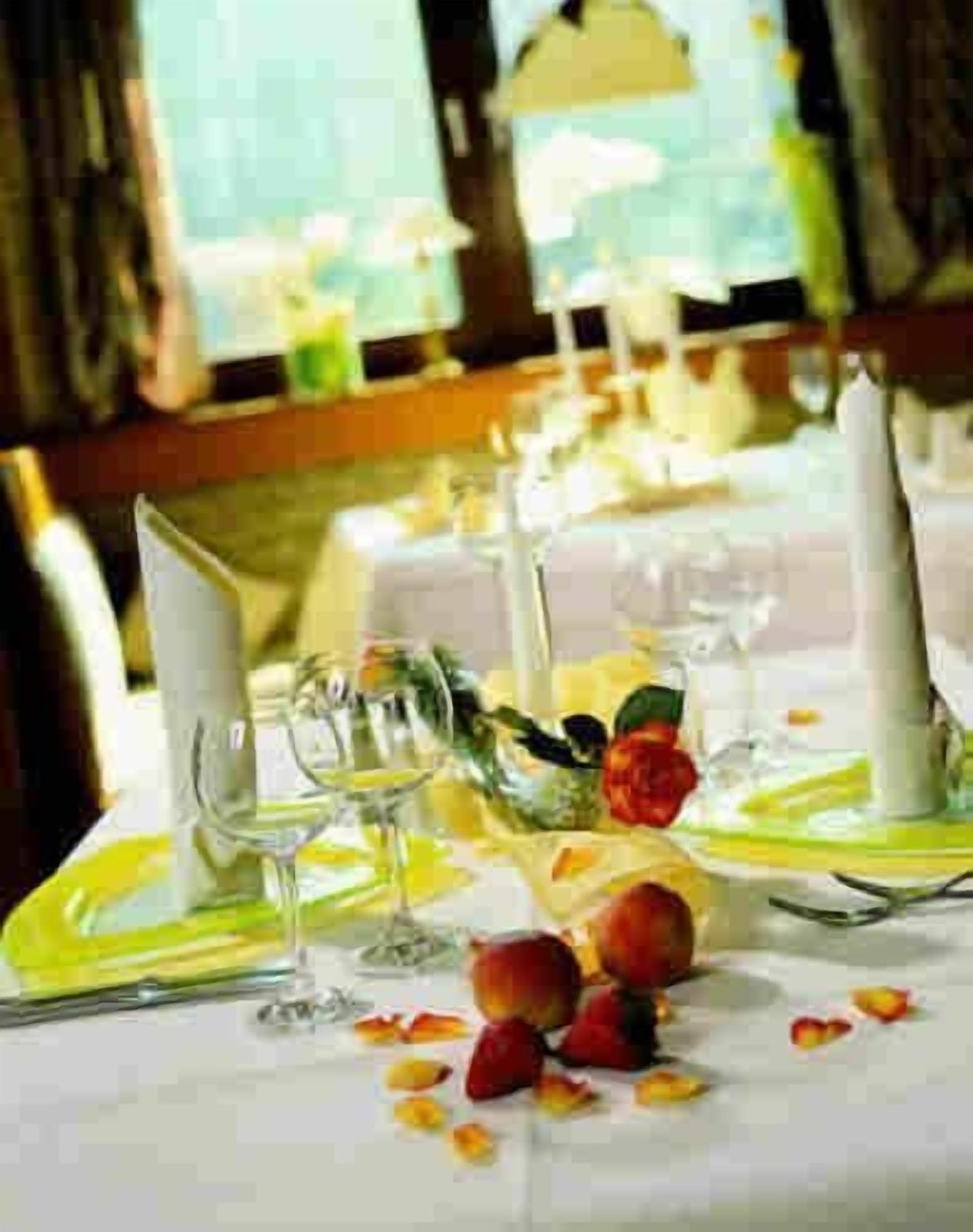 A table set for a meal with a white tablecloth, yellow plates, and clear glassware.