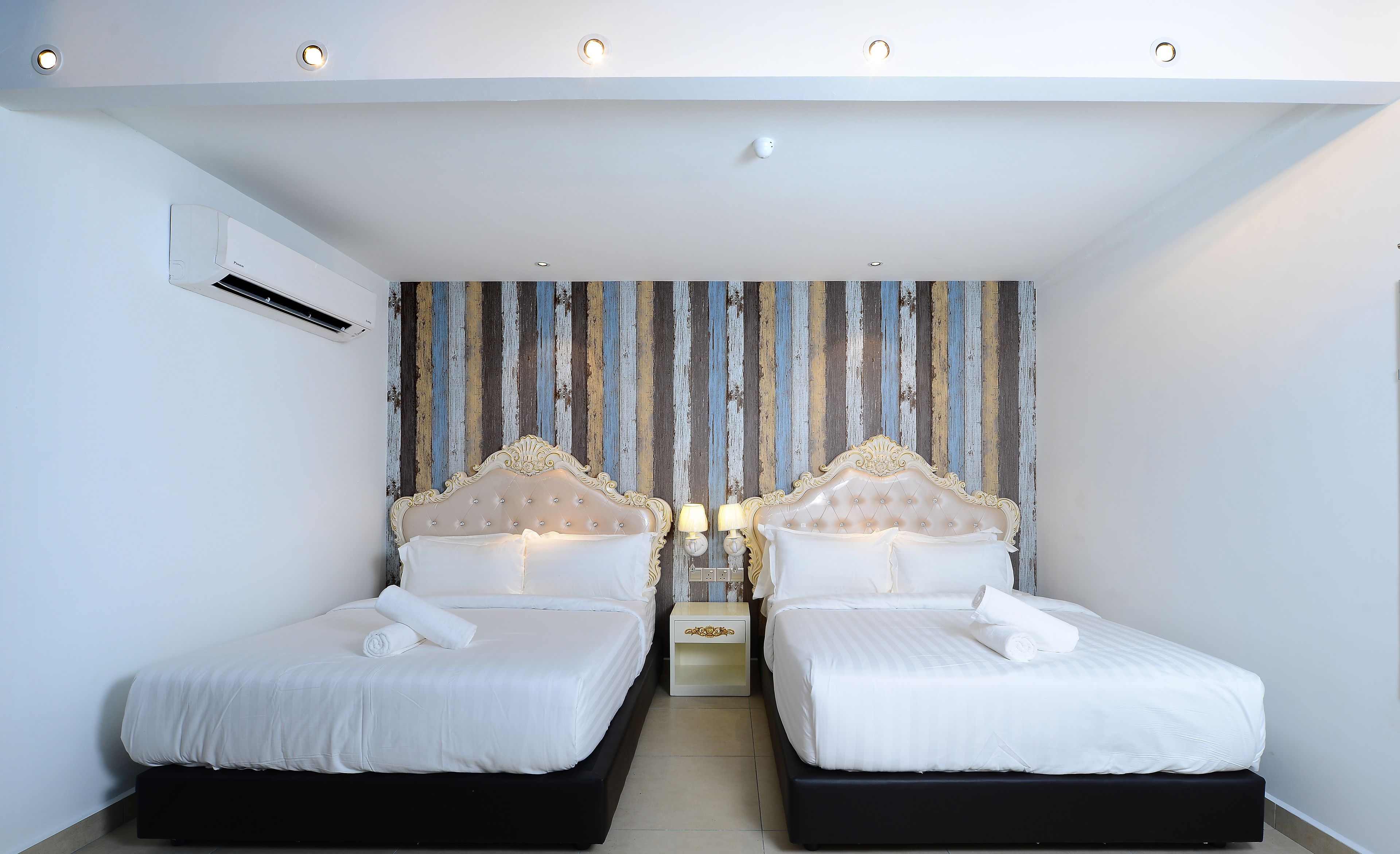 A twin room with two beds, a striped wall, and a ceiling light fixture.