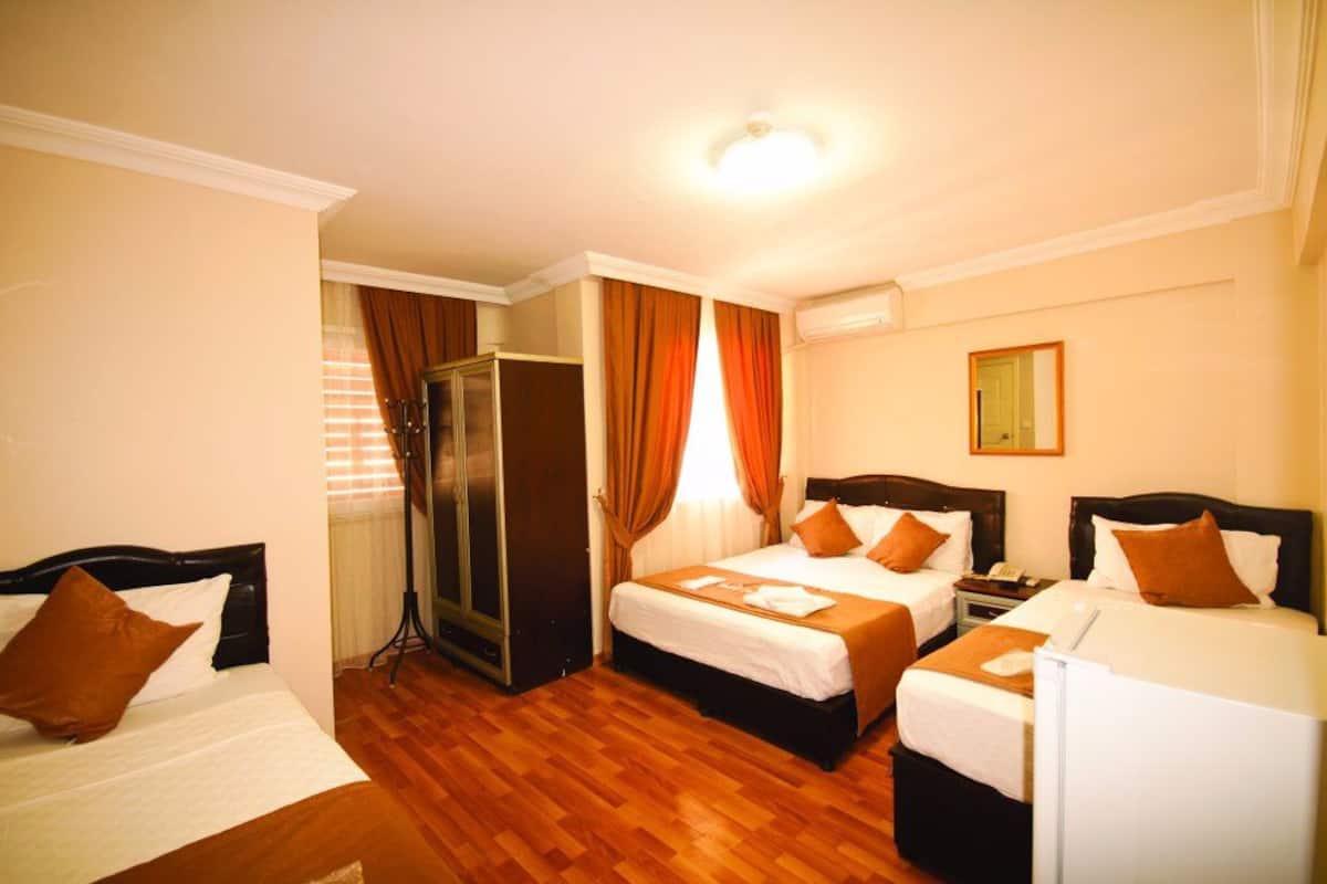 A hotel room with two single beds, a wardrobe, a desk with a chair, and a small table.