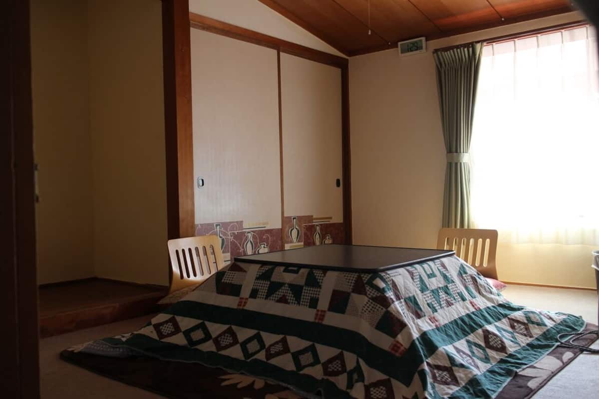 Ett rum med ett golv täckt av tatamimattor, ett lågt bord och en traditionell japansk skjutdörr.