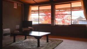 A room with a large window, a table, a television, and a heater.