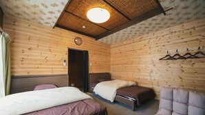 A wooden room with two beds, a sofa, a clock, and a coat rack.