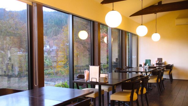 A modern dining area with large windows, wooden tables, and chairs.