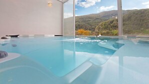 Un bain à remous offrant une vue dégagée sur un paysage montagneux grâce à de grandes fenêtres.