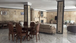 A spacious living room with a marble floor, a dining area with wooden chairs, and a fireplace.