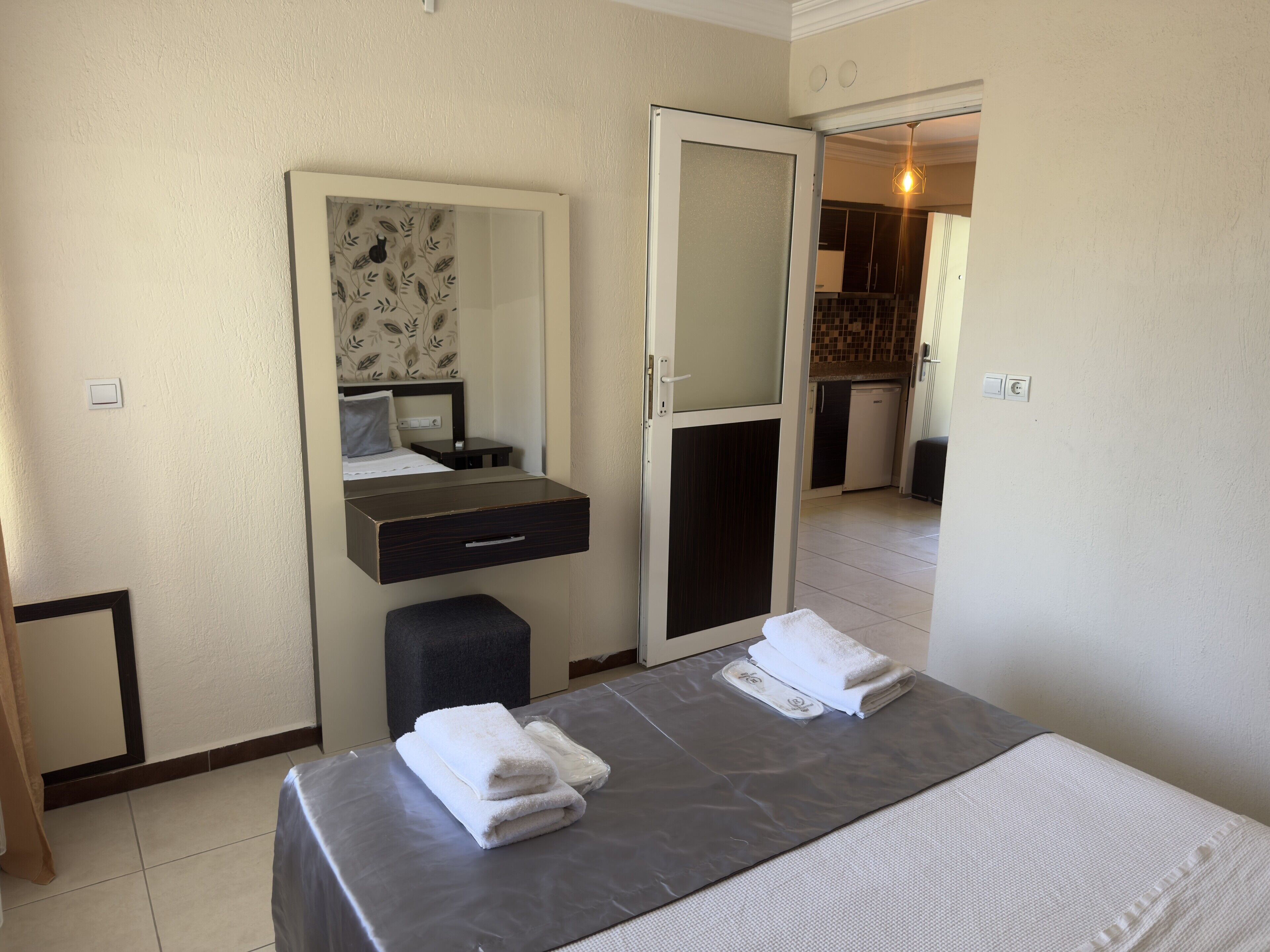 Ein Hotelzimmer mit Bett, Nachttisch, Spiegel, Kleiderschrank und einer kleinen Küchenzeile.
