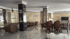 A spacious lobby with a marble floor, a large clock, and a modern seating area with sofas and chairs.