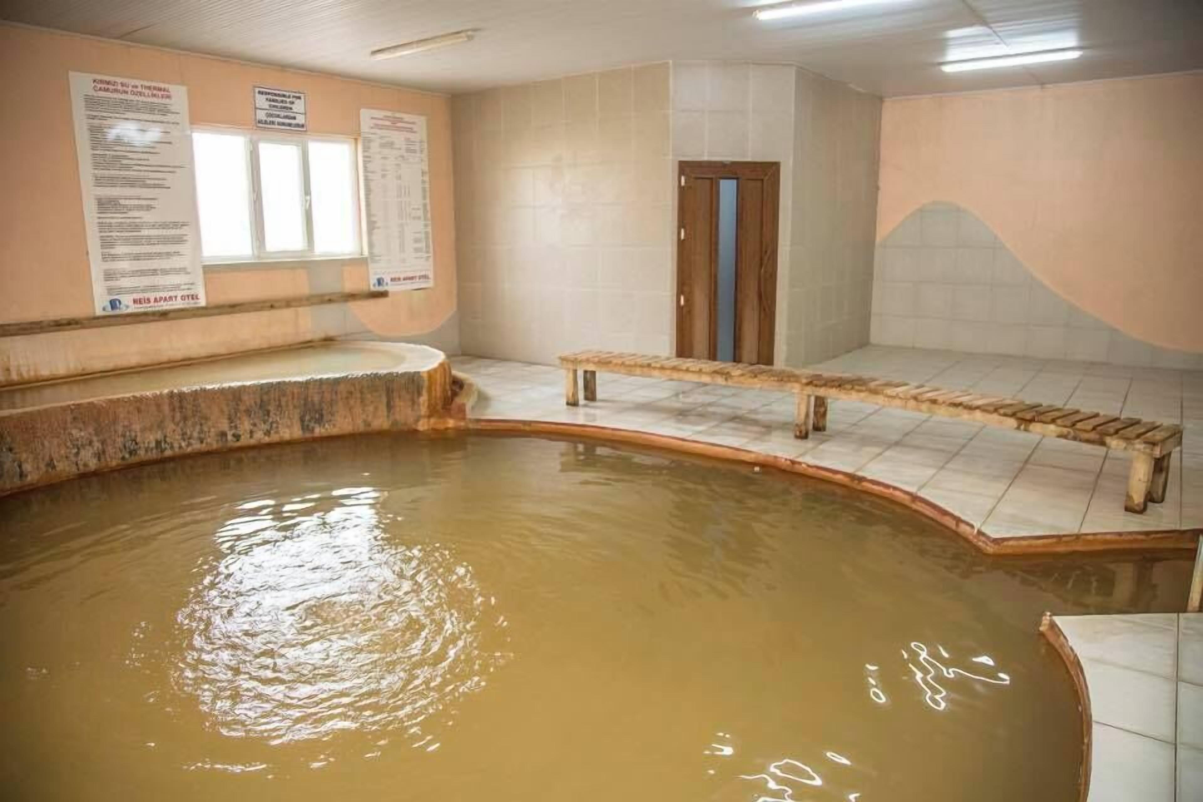 A spa area with a hot tub, wooden benches, and informational posters on the walls.