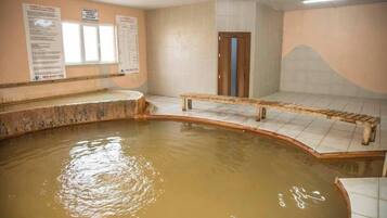 A spa area with a hot tub, wooden benches, and informational posters on the walls.