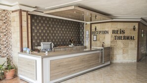 A reception area with a reception desk, a patterned wall, and a sign that reads "RECEPTION REIS THERMAL".