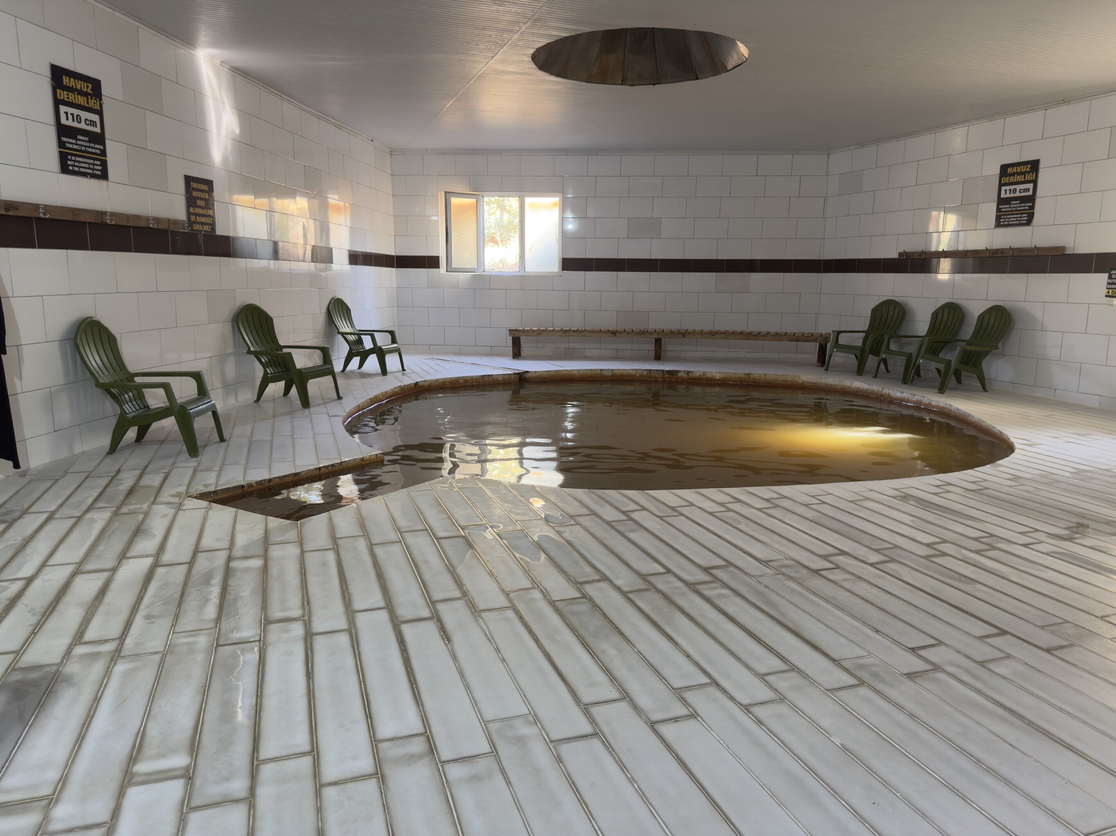 Una piscina interior con paredes de azulejos y bancos.
